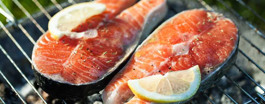 Heart healthy grilled salmon fillets with lemon herbs and olive oil on grill