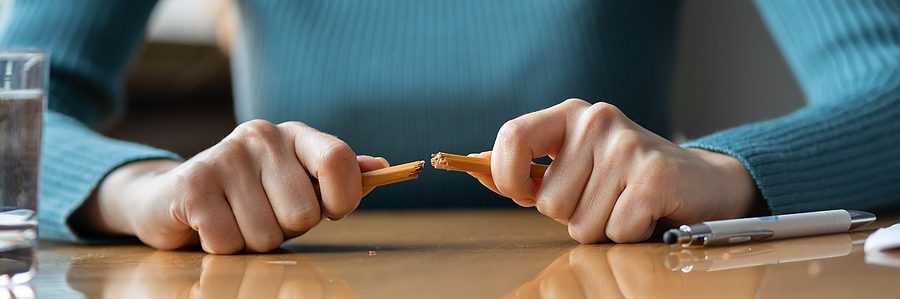 Angry female employee breaking pencil in anger