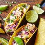 a plate of fish tacos with limes and sauce