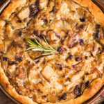 Golden-brown individual chicken pot pie with a flaky, crisp crust, garnished with a sprig of fresh rosemary and served on a rustic wooden board.