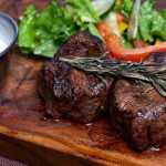 pan seared steak on board with salad