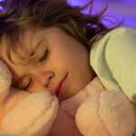 a child sleeping with a teddy bear