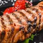 Grilled blackened salmon fillet served with lemon wedges and herbs.