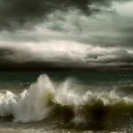 Dark storm clouds loom over a turbulent sea, with large waves crashing and churning under a dramatic, moody sky.